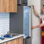Male,Worker,Repairing,Refrigerator,With,Screwdriver,In,House