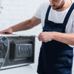 Partial,View,Of,Bearded,Handyman,Repairing,Microwave,Oven,By,Screwdriver