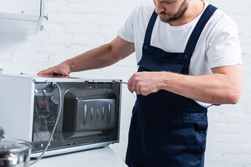 Partial,View,Of,Bearded,Handyman,Repairing,Microwave,Oven,By,Screwdriver