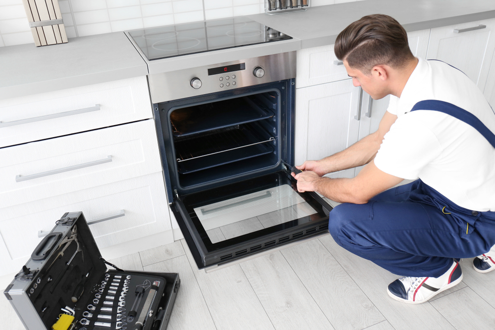 Young,Man,Repairing,Oven,In,Kitchen